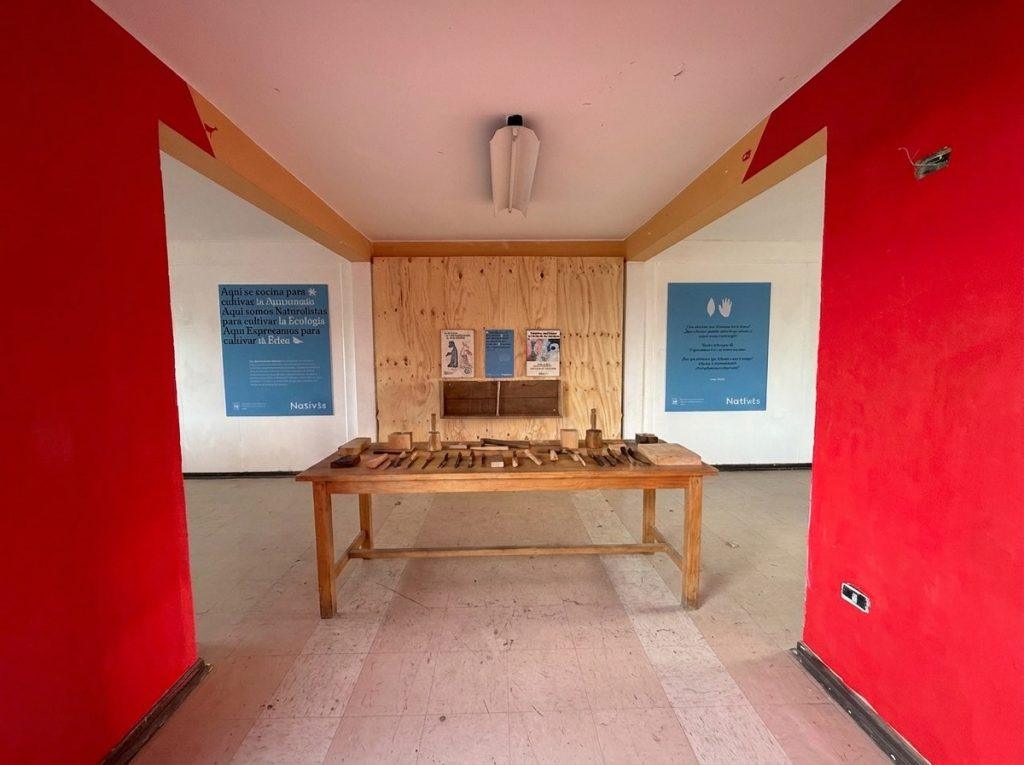 Sala de taller recuperada en la Escuela Valle Simpson, con mesa de herramientas y muros rojos