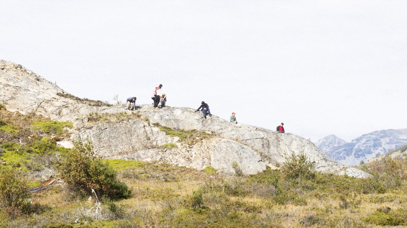 Estudiantes exploran una loma rocosa con las montañas de Aysén al fondo