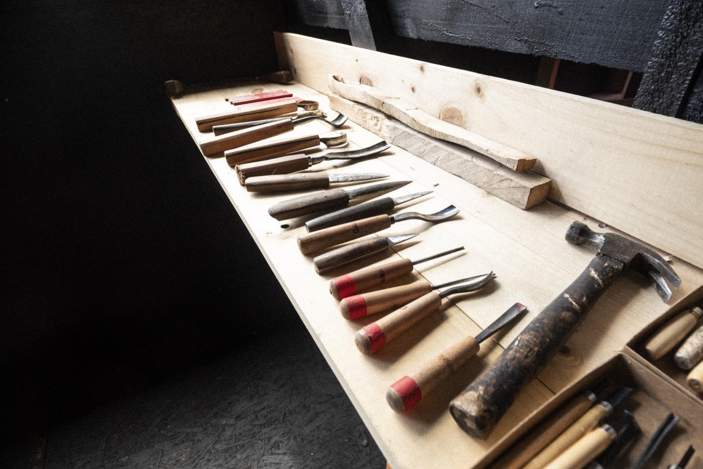 Gubias, formones y un martillo ordenados sobre el mesón del taller de tallado