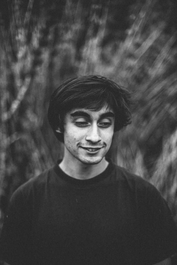 Retrato en blanco y negro de un joven con los ojos cerrados entre ramas