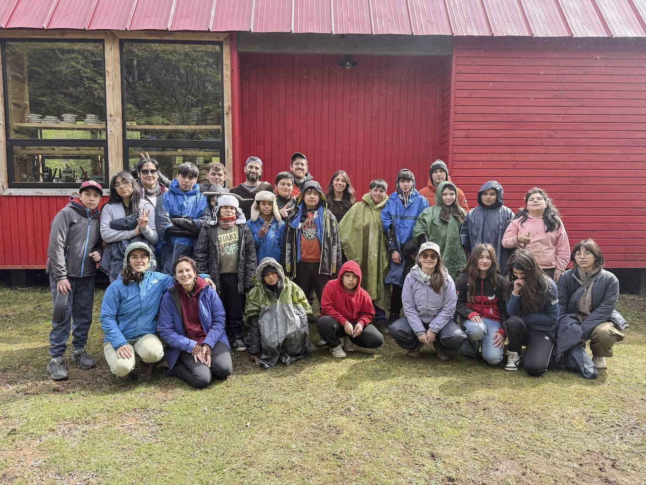 Un curso completo posa con sus educadores frente al Refugio Escuela rojo de Kaikén