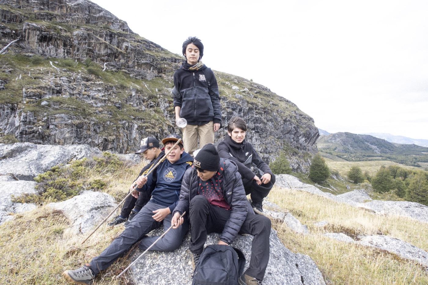 Un grupo de estudiantes descansa sobre las rocas de una cumbre con el valle de fondo